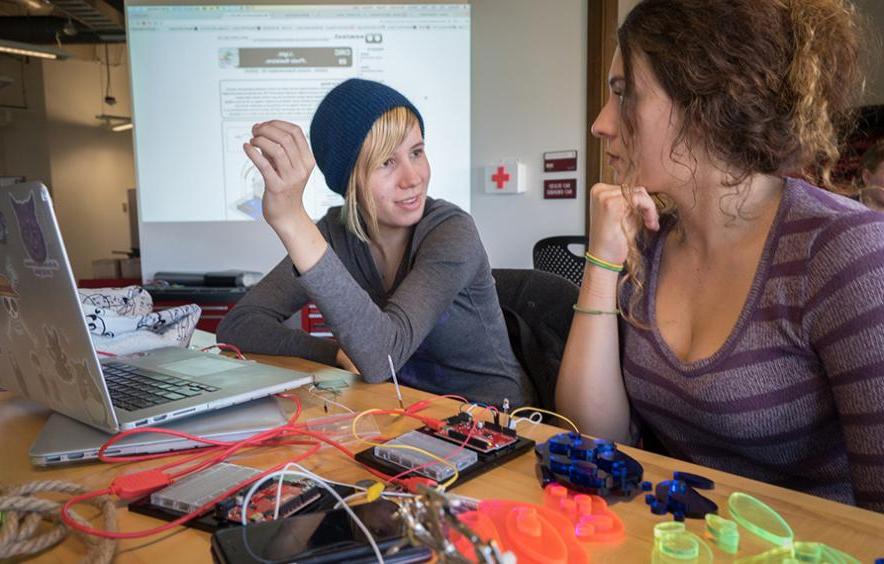 Students discuss Emergent Digital Practices while working on their laptops in a classroom.